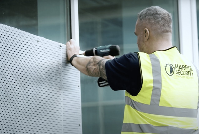A Marpol Security staff member installing some panels on a window